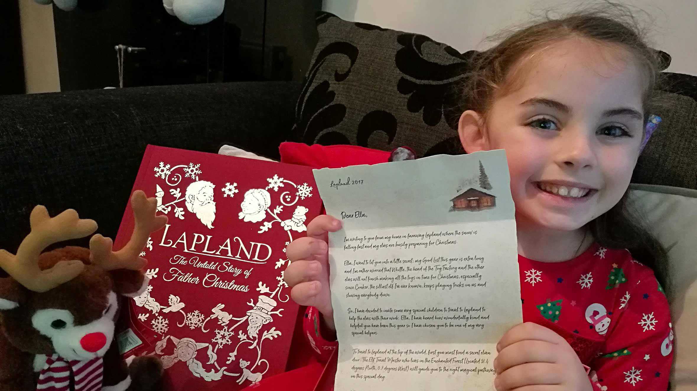 Ella smiling and holding up her letter from Father Christmas
