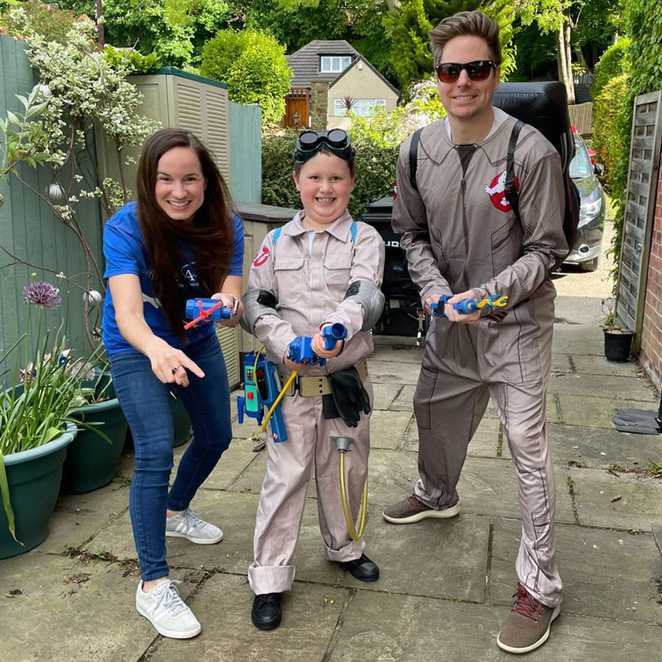 George posing outside his house with Make-A-Wish volunteer Leah and her partner.