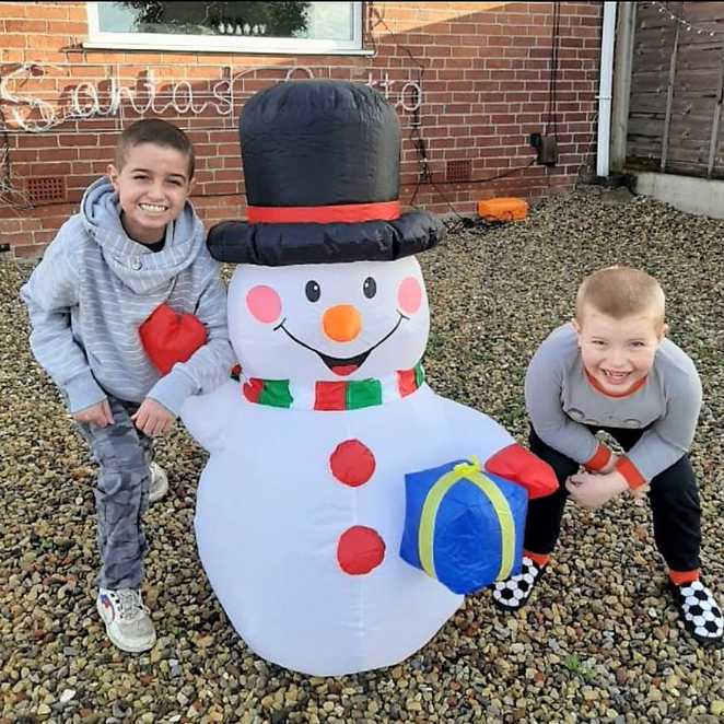 Adam and his brother Bailey, standing either side of an inflatable snowman.