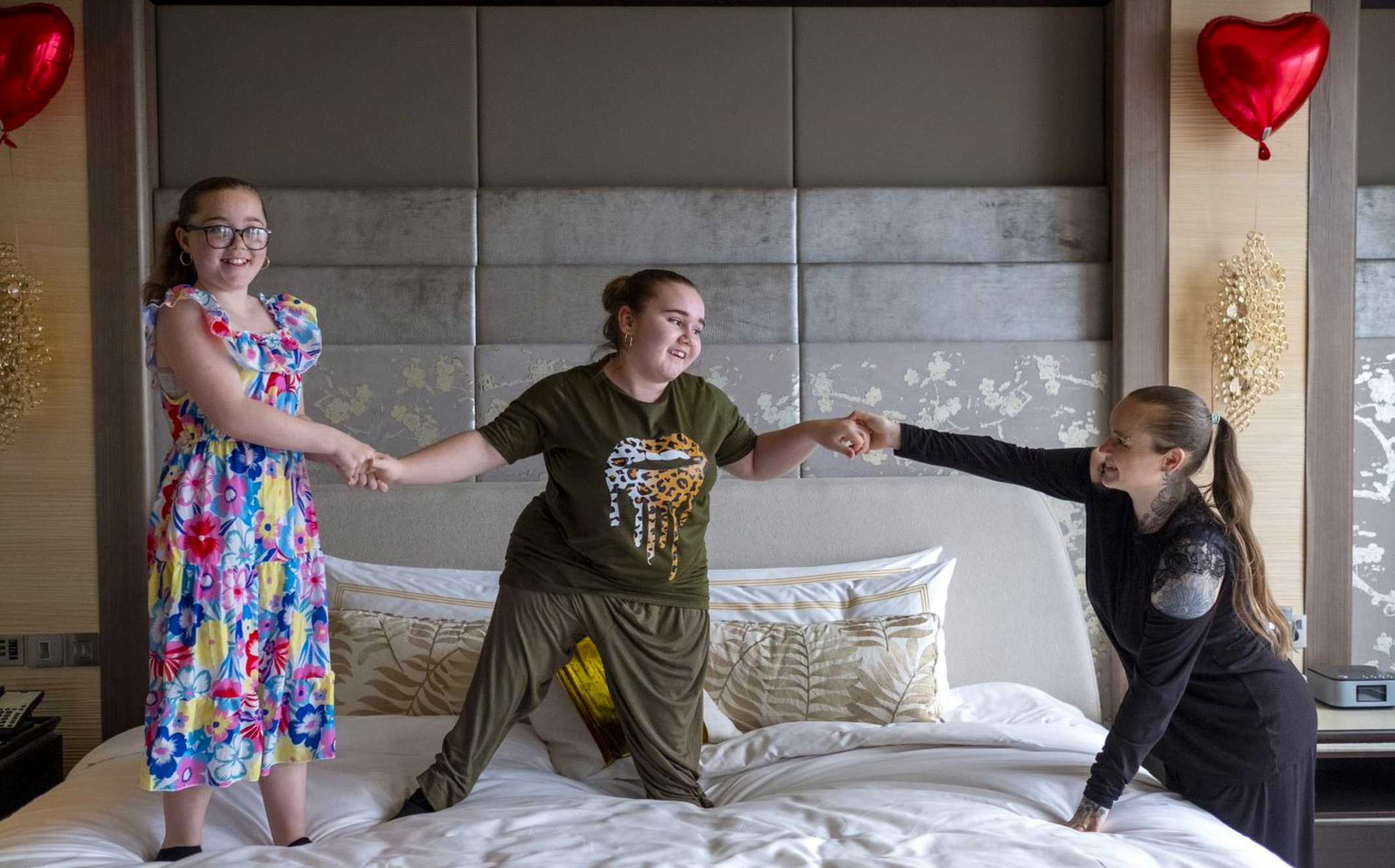 Angel jumping on the bed with her sister and mum.