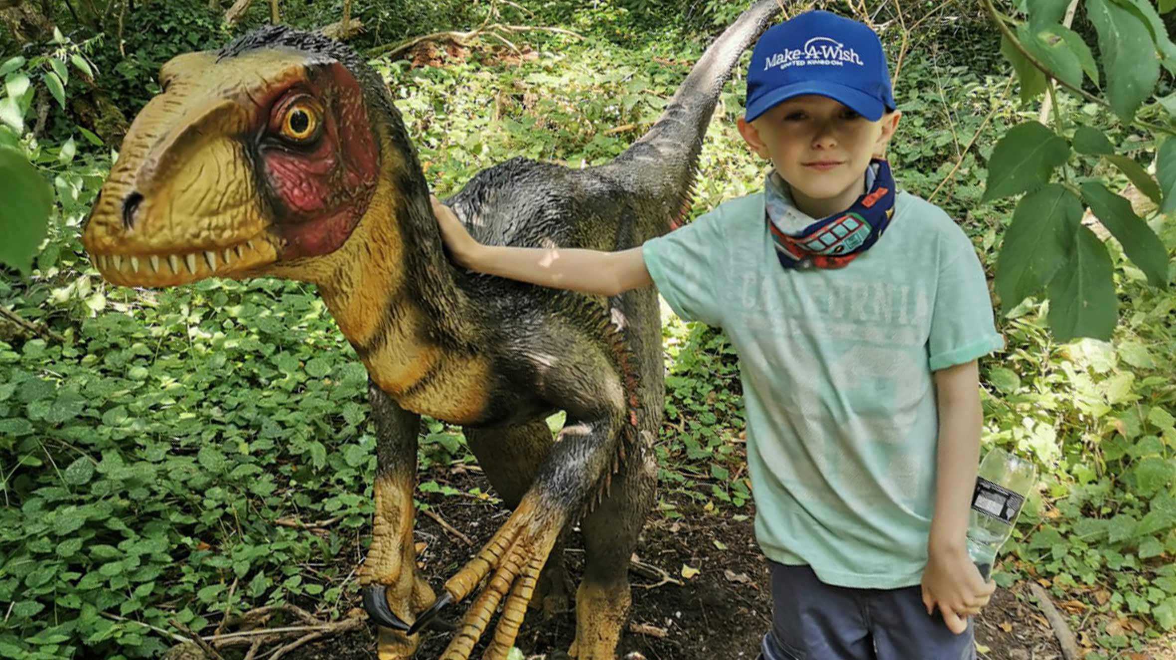 Caden standing next to a dinosaur