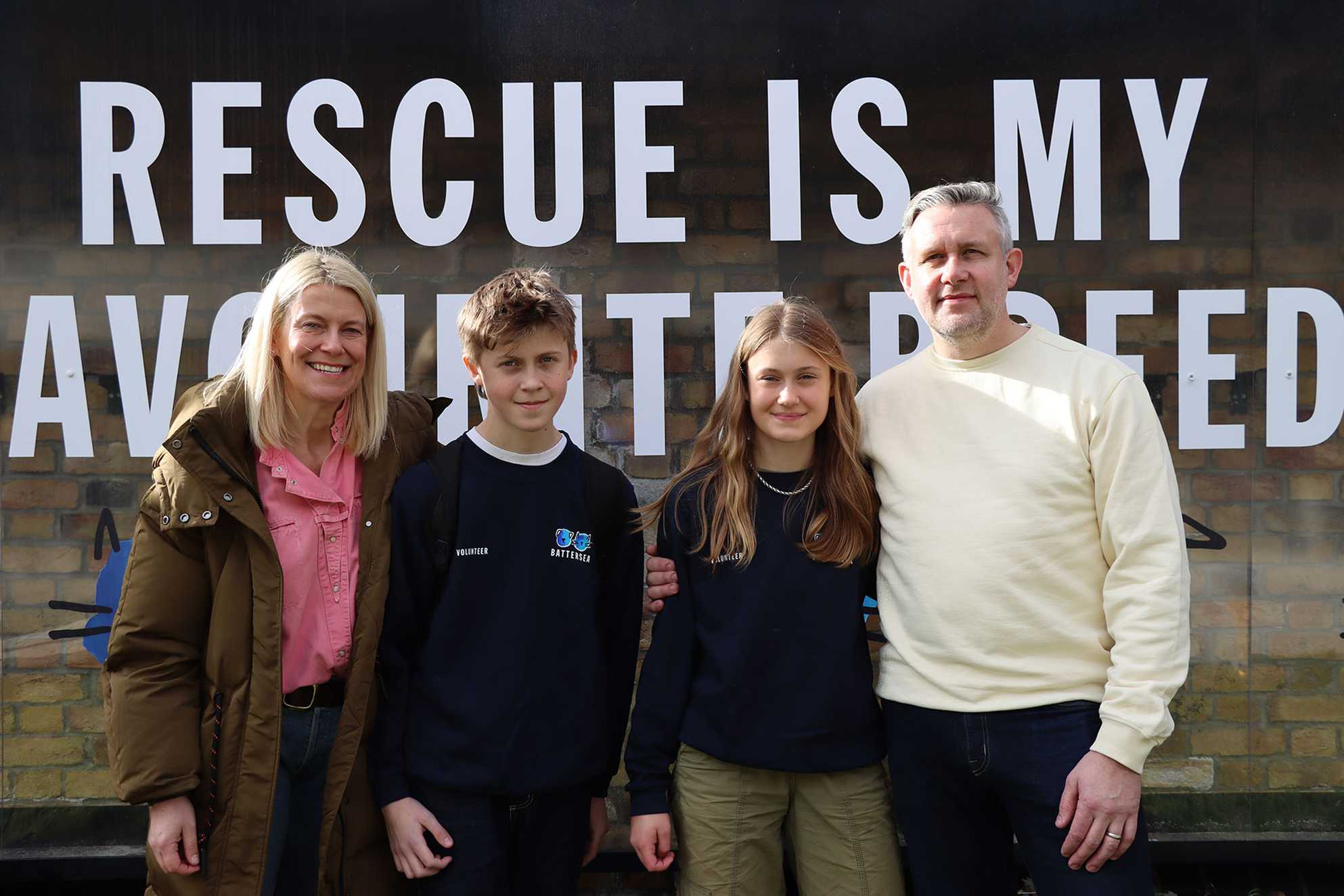 Leila and her family in front of a sign saying 'Rescue is my favourite breed'.
